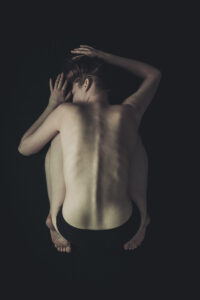 naakte vrouw plat op de grond met haar rug naar boven Fotograaf Deventer | Bedrijfsfotografie | Geënsceneerde fotografie | Studiofotografie