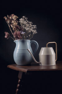 Droogbloemen in een gieter en vaas op een tafel gefotografeerd in een studio Fotograaf Deventer | Bedrijfsfotografie | Geënsceneerde fotografie | Studiofotografie