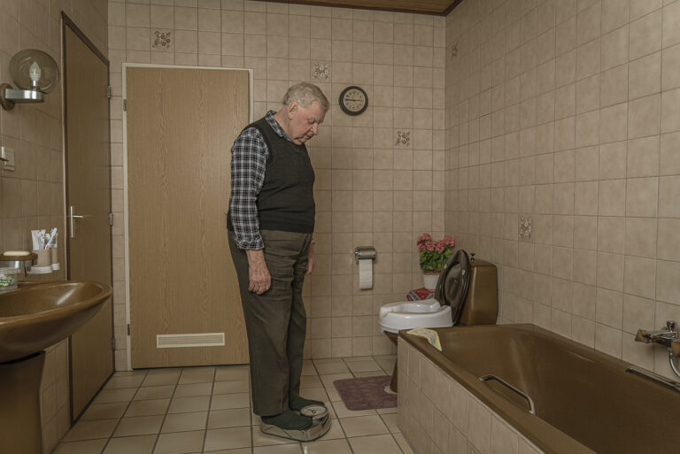 oude man op een weegschaal in een ouderwetse badkamer Fotograaf Deventer | Bedrijfsfotografie | Geënsceneerde fotografie | Studiofotografie